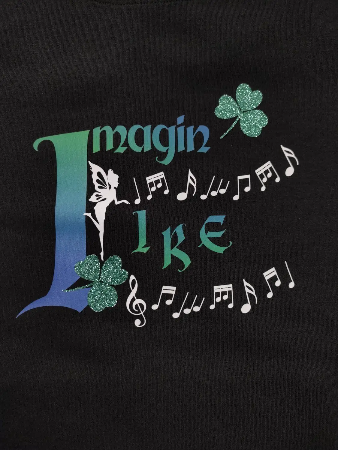 Détail logo Imagin'Lire — notes de musique et trèfle pailleté